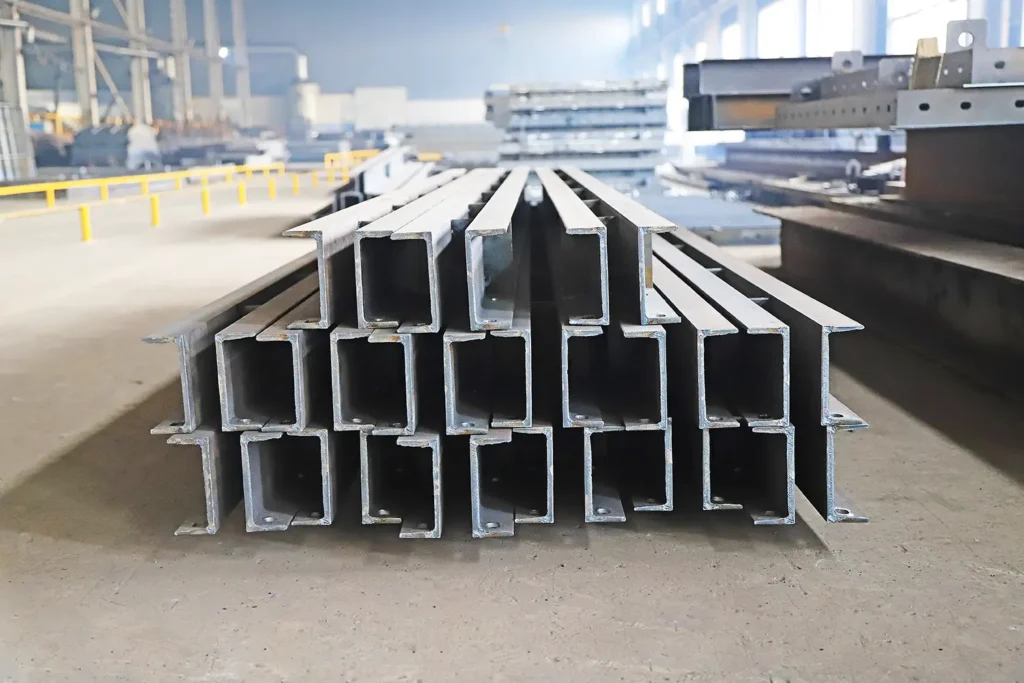 Travi in acciaio a profilo H impilate in stabilimento industriale per costruzioni e strutture metalliche